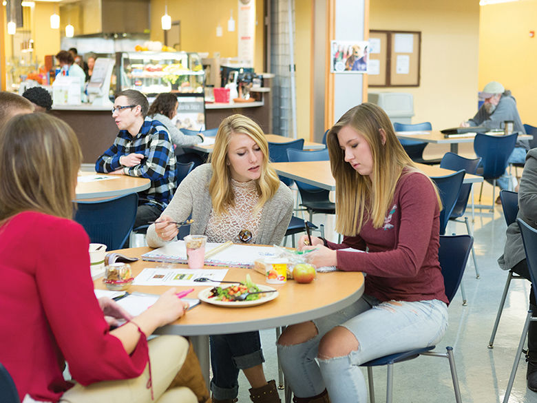 Three students sitting at a table in the campus food court