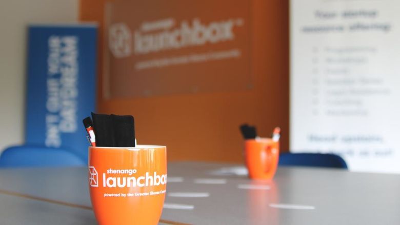 Shenango LaunchBox mug on a table with other LaunchBox advertising materials blurred out in the background
