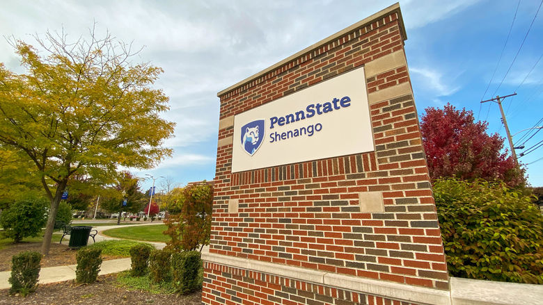 Penn State Shenango brick sign with yellow, green, and red trees in background