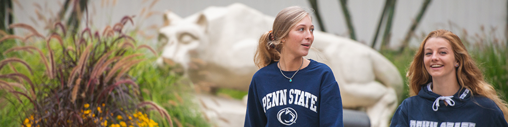 Two students walk by Nittany Lion Shrine