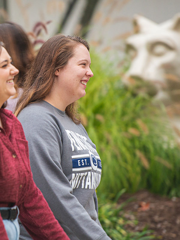 Two students walk past nittany lion shrine