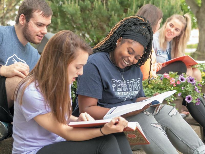 Students studying with textbooks outdoors