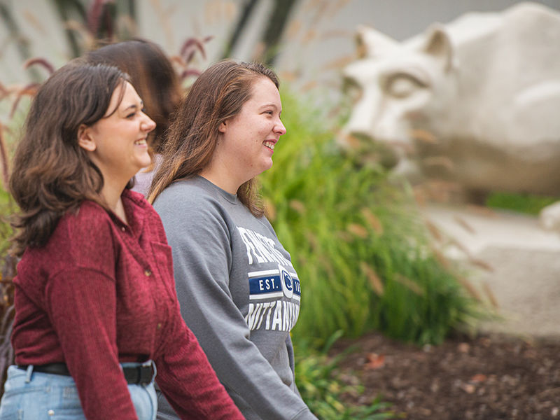 Two students walk past nittany lion shrine