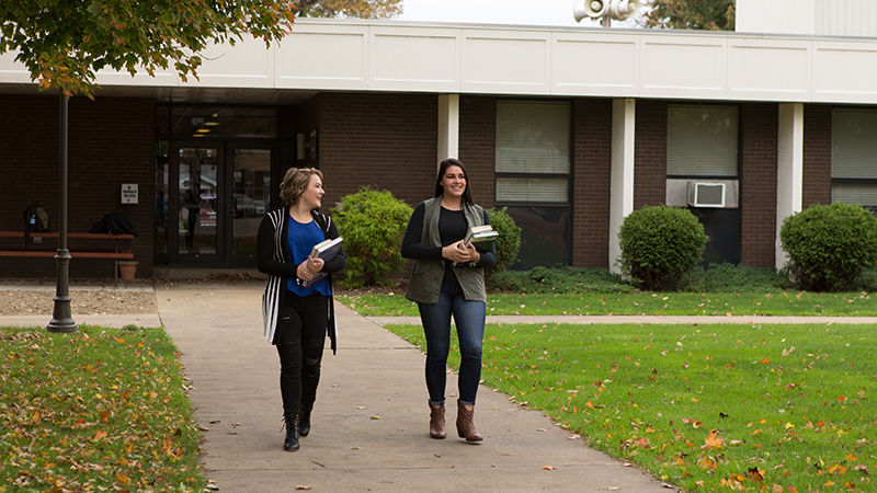 Two female students walk outside of Forker Lab on a fall day with books in hand. 