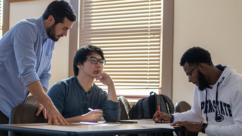 Instructor helps two students in classroom