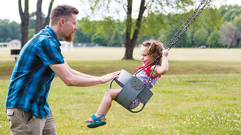 Nick Taylor pushes a preschooler on a swing