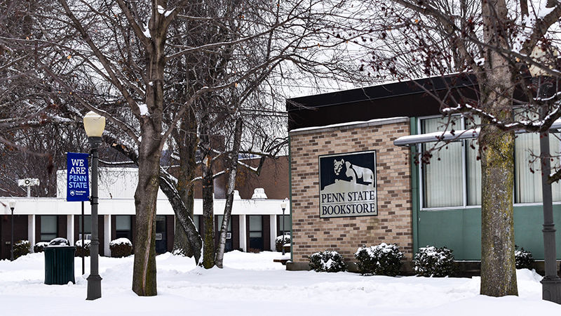 The side of McDowell Hall's bookstore logo is surrounded by leafless trees and snow-covered ground. 