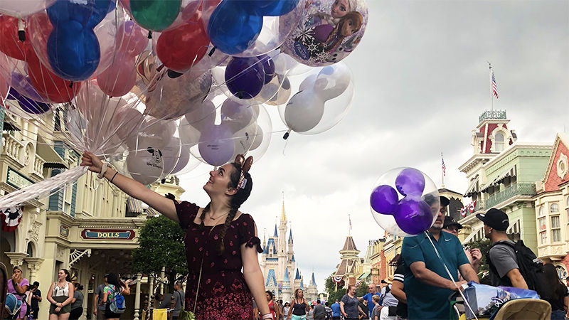 Young woman holding a bunch of balloons in an amusement park.