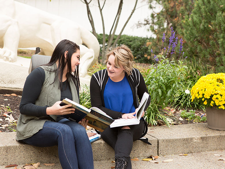 2 student reading textbooks outside