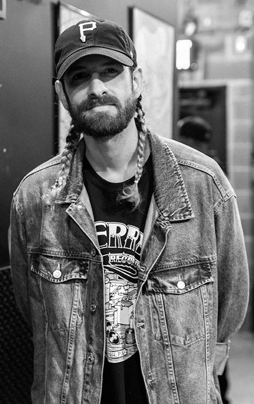 International DJ Adam Cucitrone wearing a baseball cap and a jean jacket
