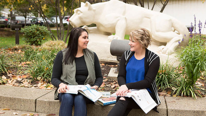Two business student study by the nittany lion shrine