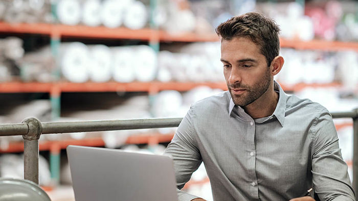 Supply chain manager working on computer is warehouse