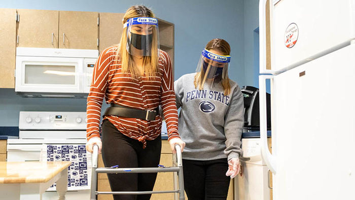 Two occupational therapy students use adaptive devices to navigate kitchen
