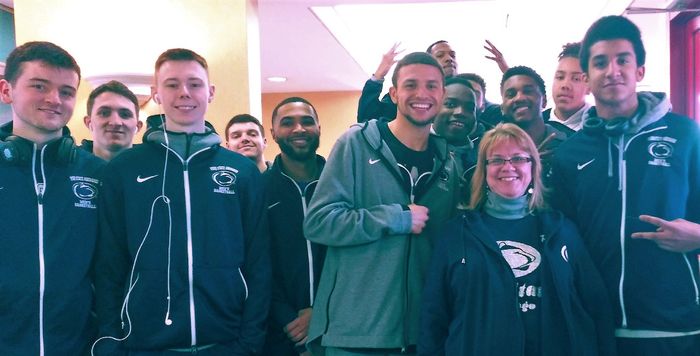 One woman standing with a group of college-aged, male basketball players.