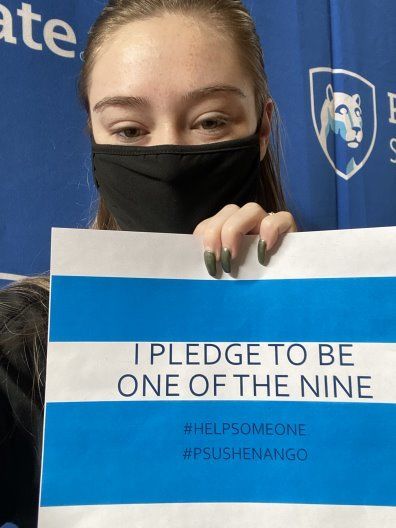 Masked student holding sign that says "I pledge to be one of the nine"