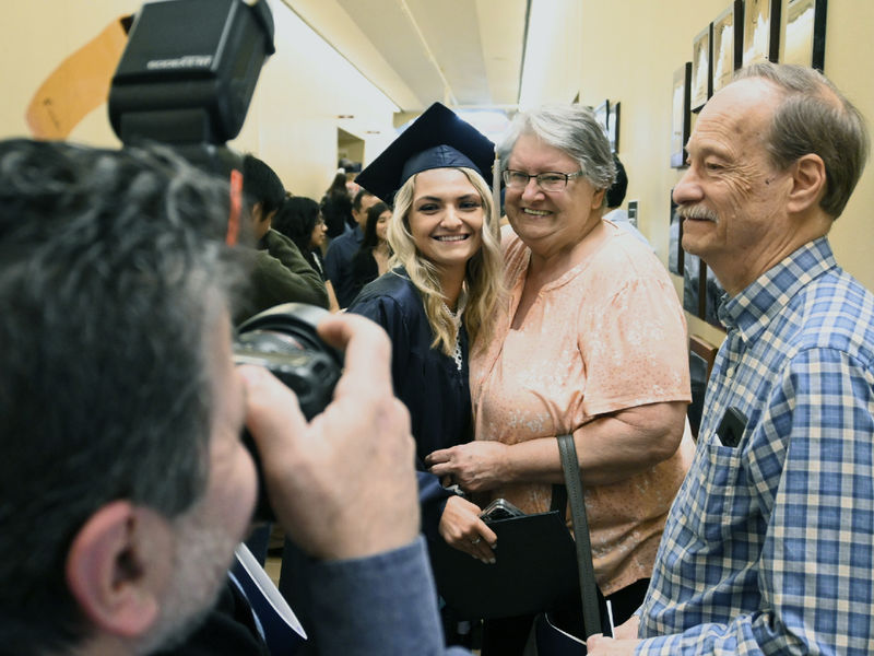 Graduate Hanna Morgan, in cap and gown, pauses for photo opportunities with her grandparents.