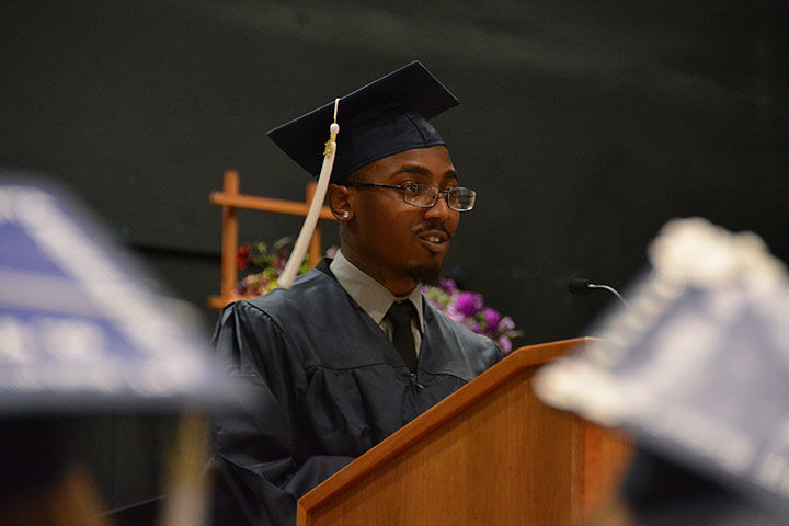 Alijah Hasan-Douglas speaks at a podium in his graduation cap and gown. 