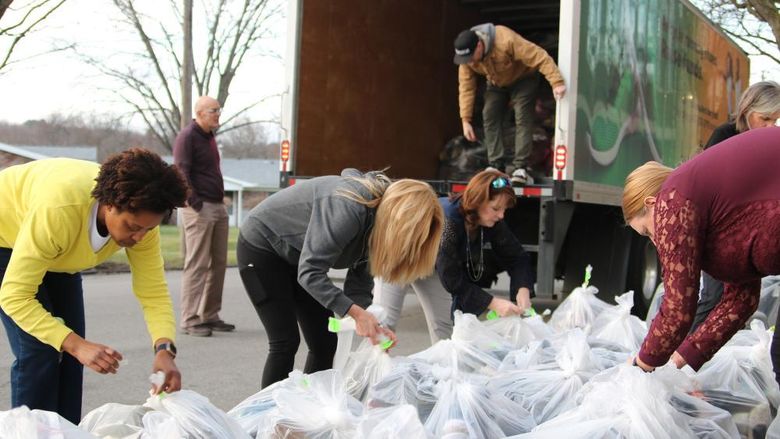 Group of people tagging large plastic bags full of shoes and loading them into a box truck