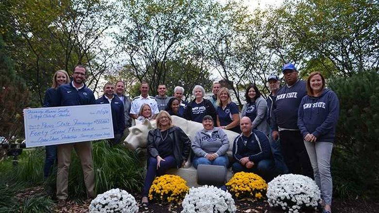 A group of men and women in front of the Nittany Lion at Shenango campus.