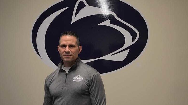 Man stands in front of the Nittany Lion Athletic mark