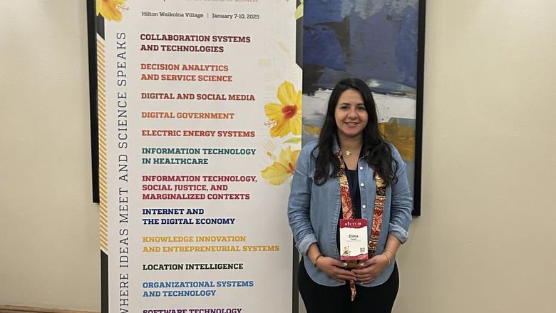 Dima Rabadi poses next to an HICSS Conference sign