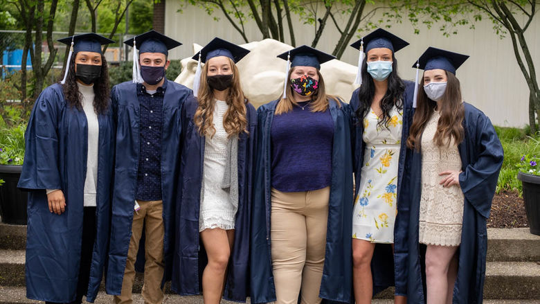 Six graduates posing together in front of lion shrine