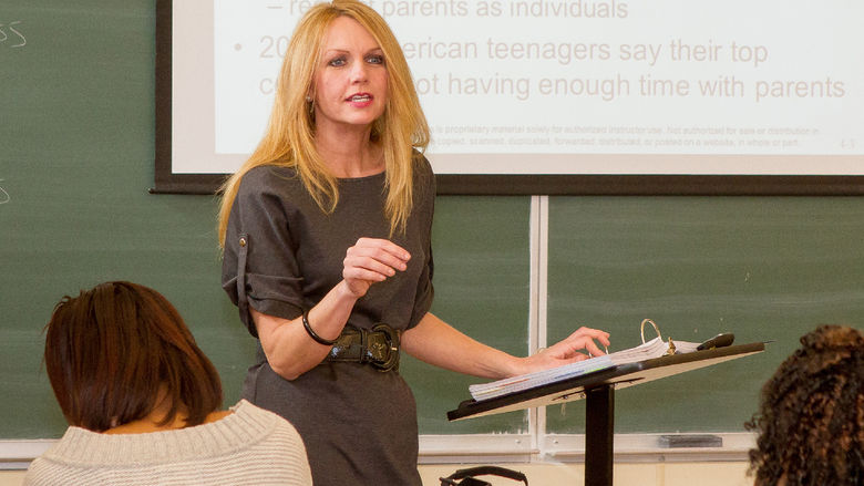 Roxanne Atterholt standing at a podium lecturing to students in a classroom