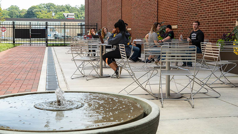 A fountain in the foreground and a courtyard with students sitting in the background