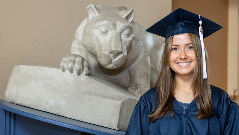Penn State Shenango graduate next to mini nittany lion shrine