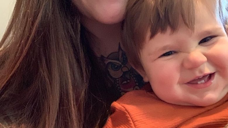 A young, brunette woman holding a toddler.