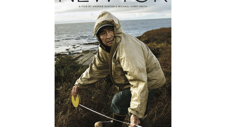 A promotional poster for the film "Newtok," showing a person in a raincoat on a coast
