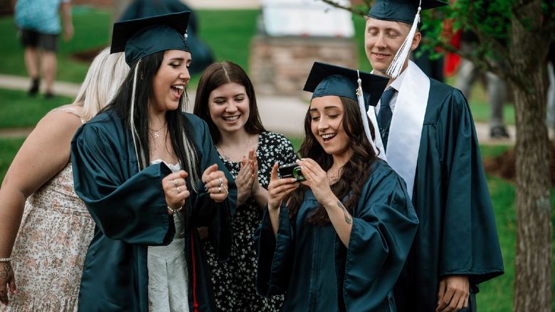 Graduates and students gather to look at camera photo