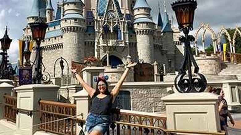 A young woman in front of Disney World's Magic Kingdom.