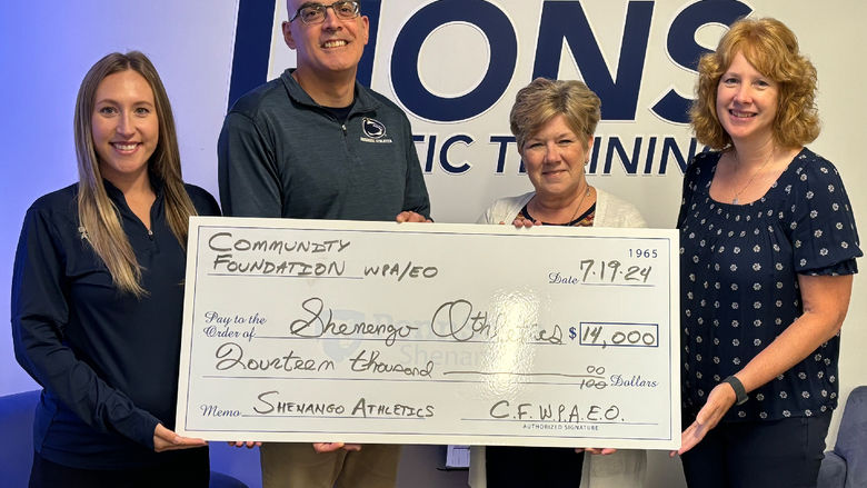 Group photo of four people holding an oversized check