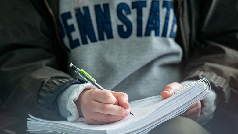 Student holding pencil writing in a notebook