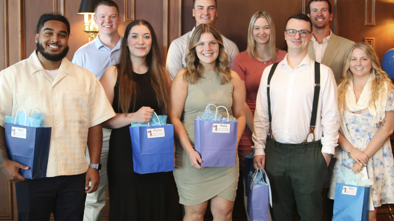 Group of nine students pose with blue gift bags
