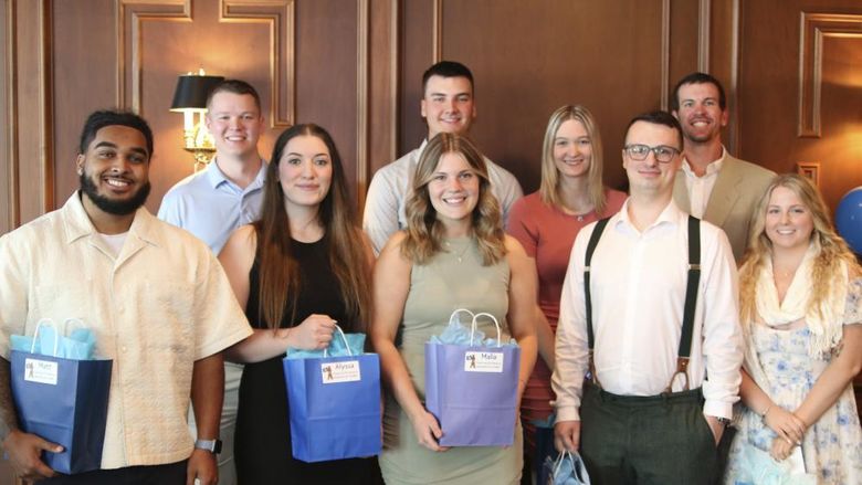 Group of nine students pose with blue gift bags