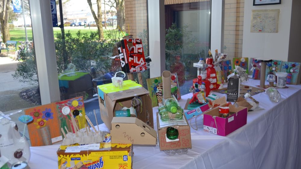 Several upcycled art projects on a table in the campus' Atrium area