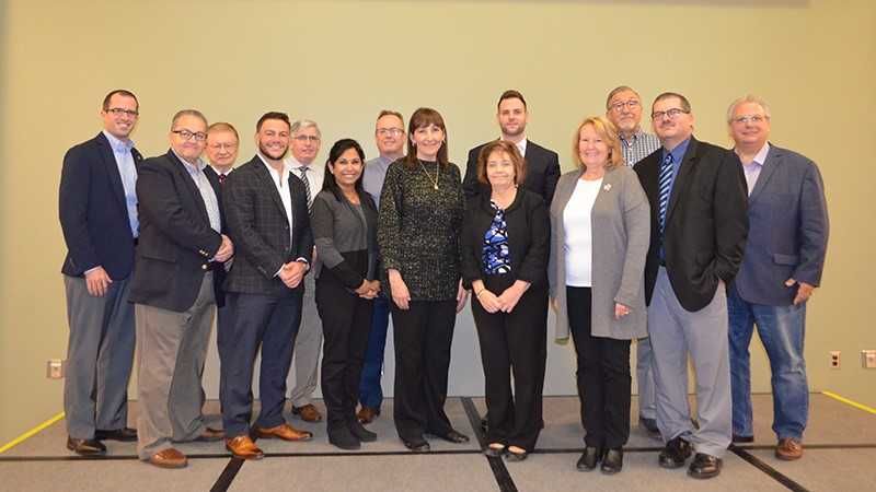 Several men and women from Shenango's advisory board stand together to get their picture taken.