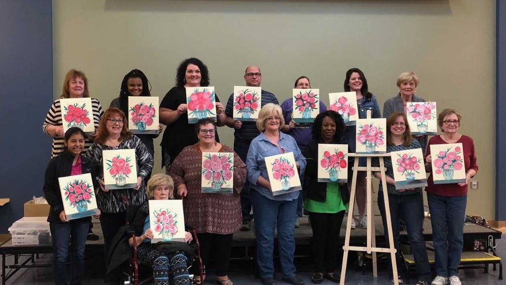 Group of women and men holding their newly painted pictures.