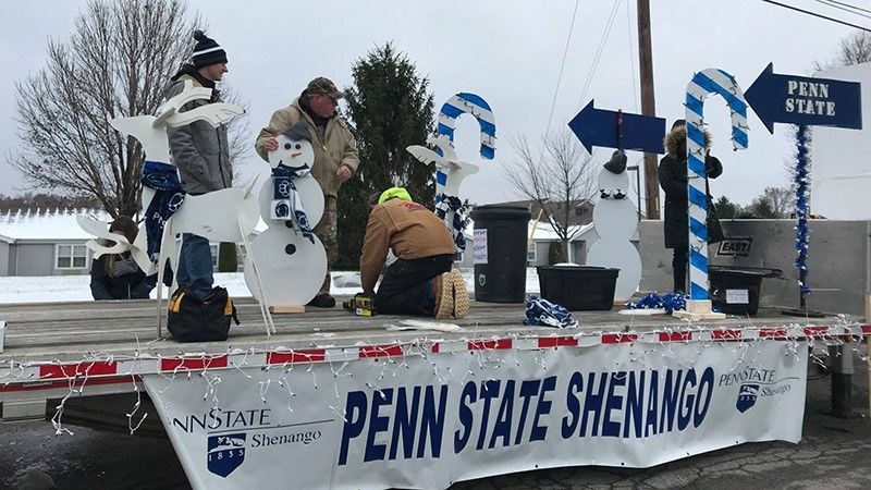 People decorating the back of a semi truck flat bed for the holiday parade