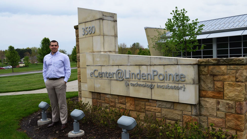 Riley Atterholt stands by the eCenter@LindenPointe front lawn sign