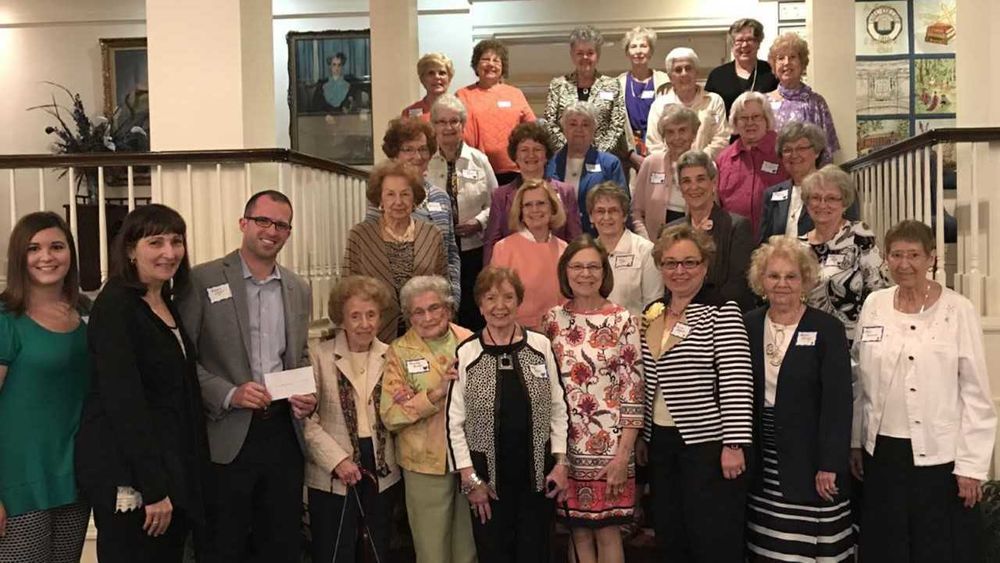 A large group of women and one man pose for a picture.