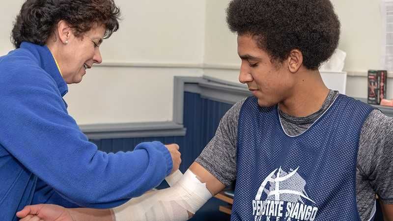 A woman wraps an athletes arm.