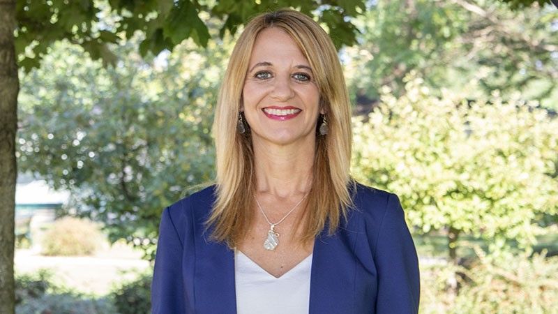 A female faculty member standing outside by a tree