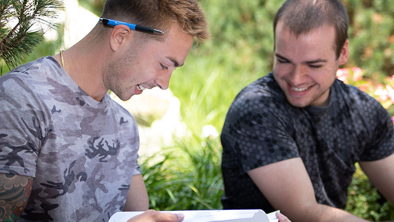 Two male students looking at a book.