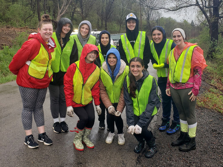 Group of people pose for a photo outside wearing bright green safety vests