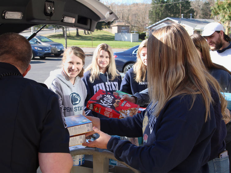 Students moving food and supplies into the back of a police vehicle