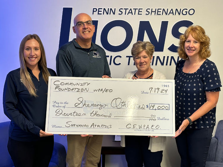 Group photo of four people holding an oversized check