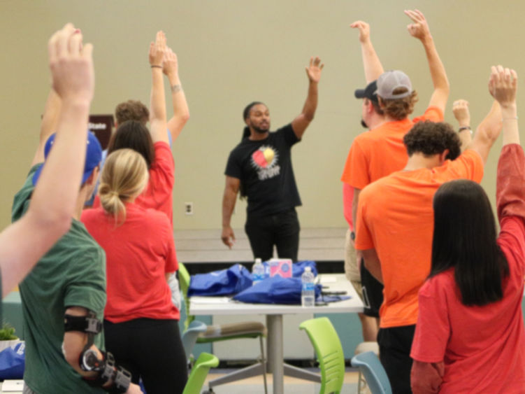 Speaker in front of room while listeners raise hands